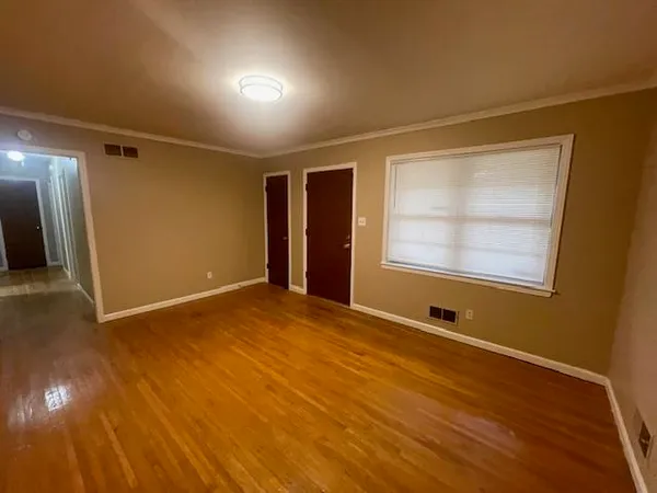 a view of an empty room with wooden floor and a window