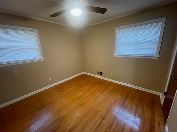 an empty room with wooden floor and windows