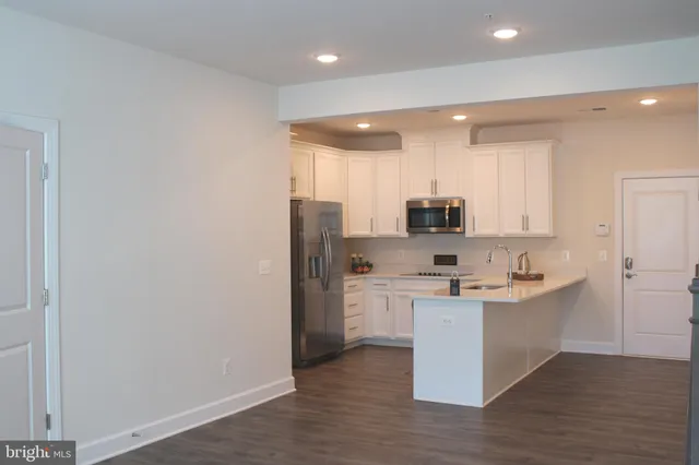 a kitchen with stainless steel appliances a sink a stove a refrigerator and cabinets