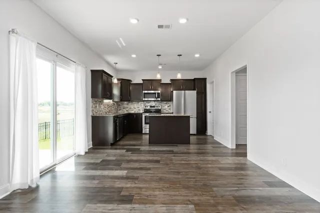 a large kitchen with stainless steel appliances kitchen island a large counter top and a wooden floors