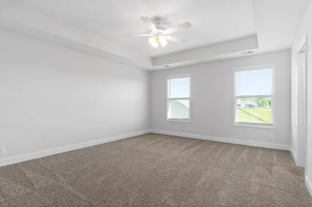 an empty room with windows and ceiling fan