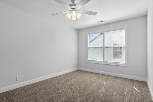 an empty room with a chandelier fan and closet