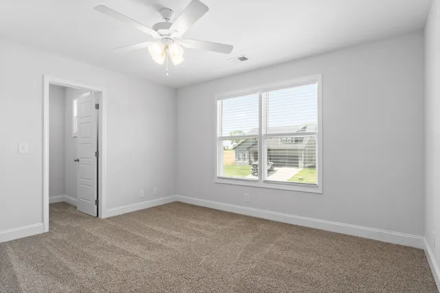 an empty room with a window and a fan