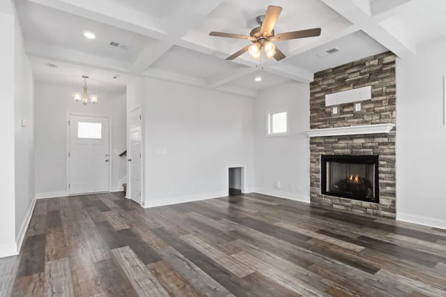 an empty room with wooden floor a ceiling fan a fireplace and windows