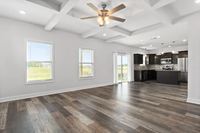 an empty room with windows and ceiling fan kitchen view