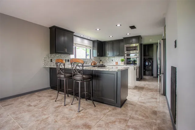 a kitchen with stainless steel appliances a sink a stove a refrigerator cabinets and a dining table