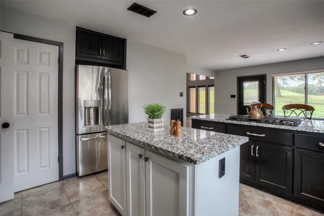 a kitchen with stainless steel appliances granite countertop a sink and a refrigerator
