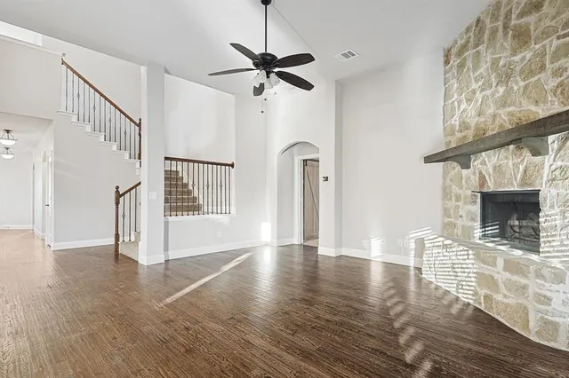 a view of an empty room with wooden floor fireplace and a window