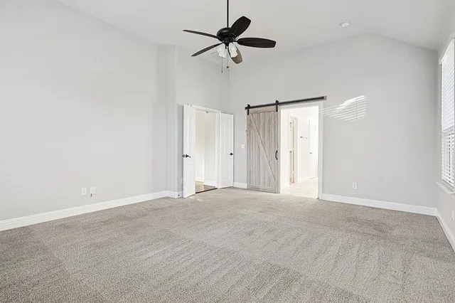 an empty room with chandelier fan and windows