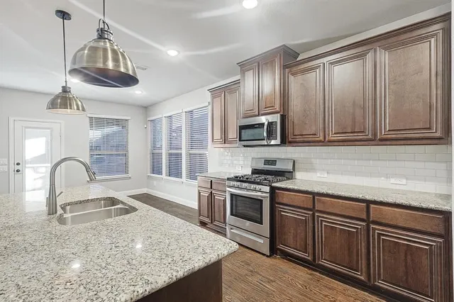 a kitchen with wooden cabinets a sink and stainless steel appliances