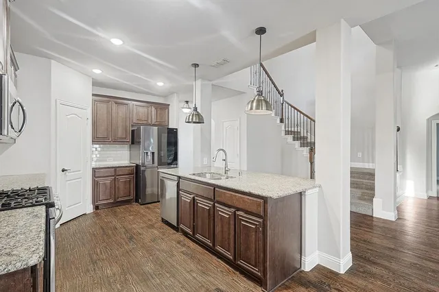 a kitchen with center island wooden floor and a chandelier