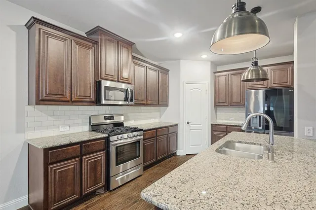 a kitchen with stainless steel appliances granite countertop a sink a stove and a refrigerator