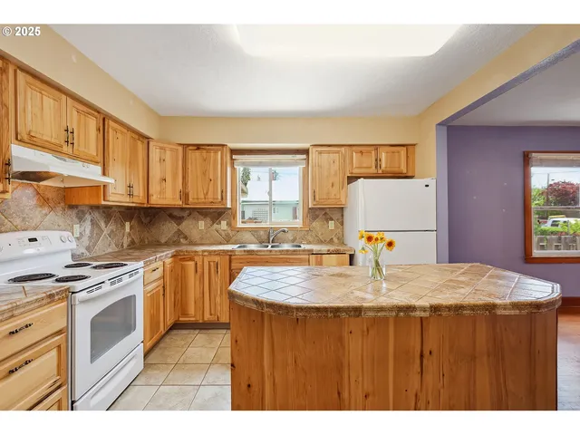 a kitchen with kitchen island granite countertop a stove a sink and a refrigerator