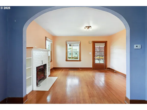 a view of empty room with fireplace and wooden floor