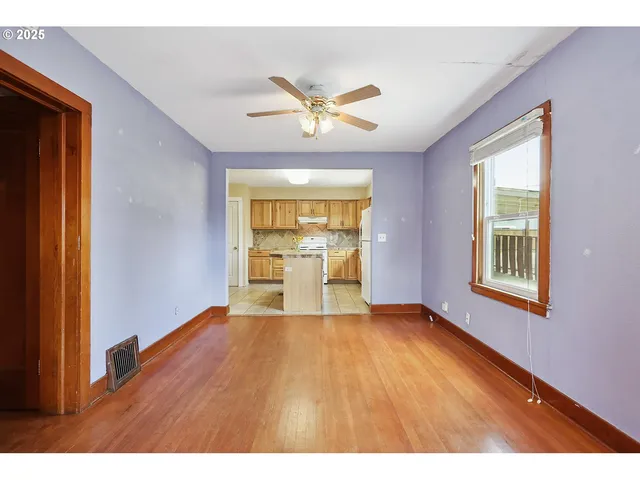 a view of an empty room with window and wooden floor