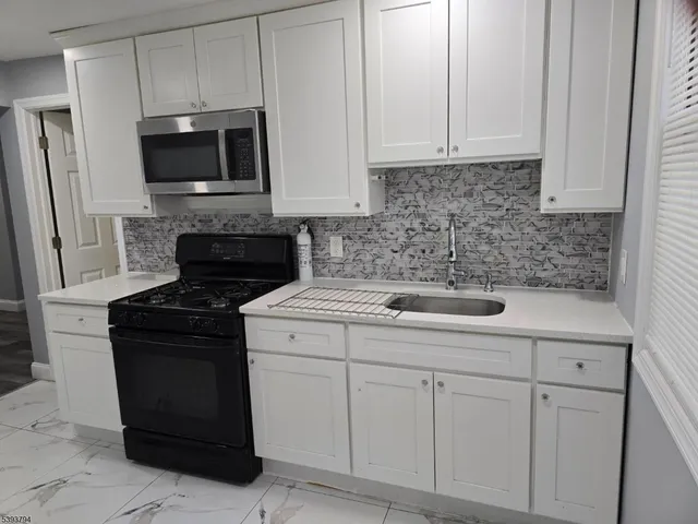 a kitchen with white cabinets and black appliances