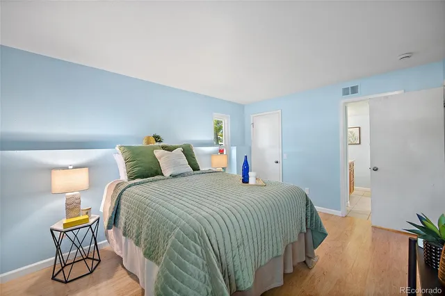 a bedroom with a bed a chair and potted plant on the dresser