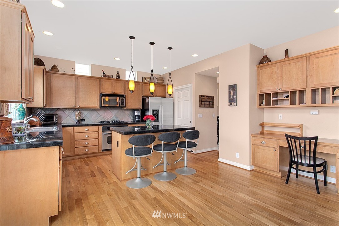 258 Lyons Place Northeast Renton, WA 98059 - Photo 13 of 25 a kitchen with stainless steel appliances kitchen island granite countertop a stove a refrigerator a kitchen island a dining table and chairs with wooden floor