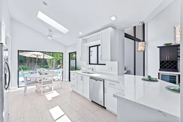 a large white kitchen with a large window and stainless steel appliances