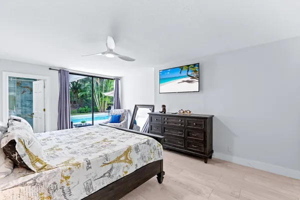 a bedroom with a bed a large window and potted plant on the dresser