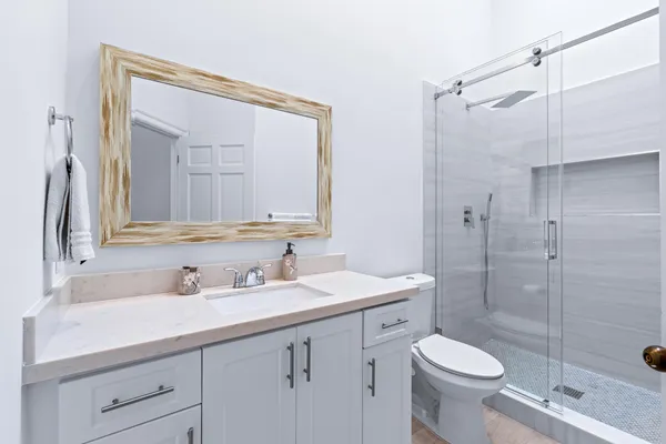 a bathroom with a sink a toilet a mirror and shower