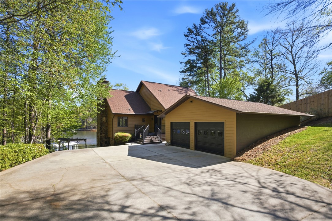 This lakeside residence features a welcoming exterior with an attached garage and a private driveway.