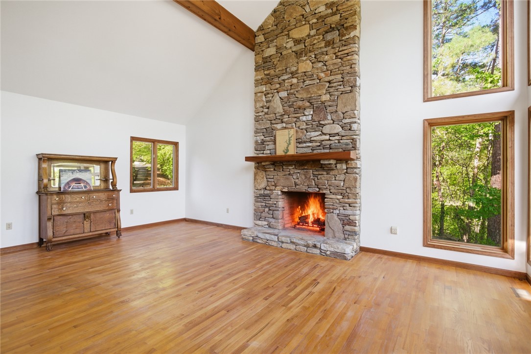 120 Farris Sandra Road West Union, SC 29696 - Photo 7 of 50 This living room features a grand stone fireplace and large windows overlooking lush greenery.