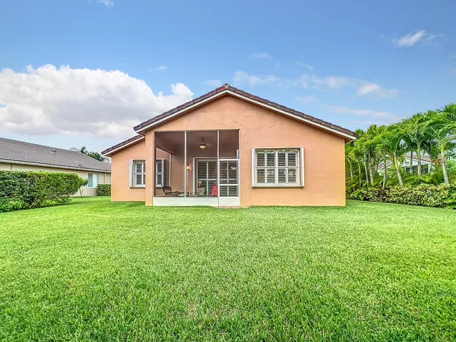 a view of yellow house with a swimming pool and lawn chairs next to a road
