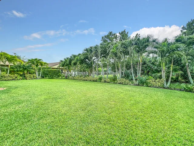 a white house with a large pool and lawn chairs under an umbrella