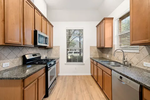 a kitchen with stainless steel appliances granite countertop a sink stove and cabinets