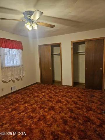 a view of an empty room with a chandelier fan