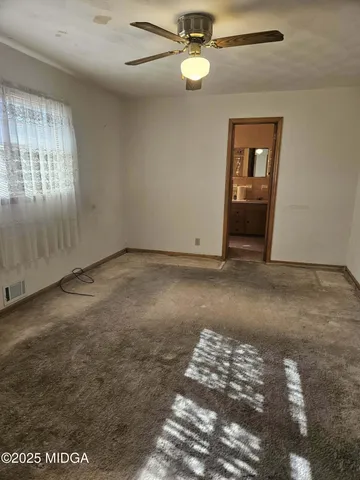an empty room with windows and ceiling fan