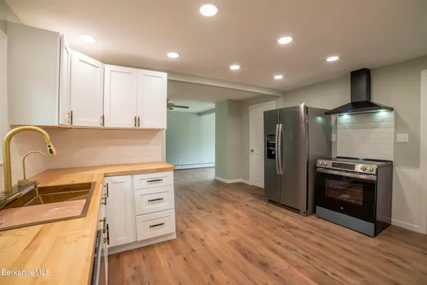 a kitchen with stainless steel appliances granite countertop a refrigerator a stove and a wooden floors