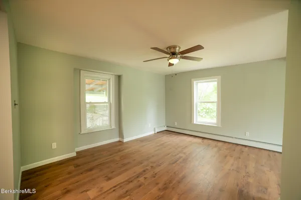 a view of an empty room with a window and wooden floor