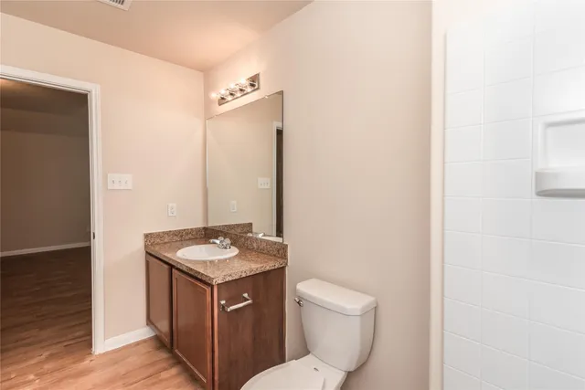 a bathroom with a granite countertop toilet sink and mirror