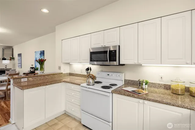 a kitchen with granite countertop white cabinets and white appliances
