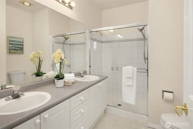 a bathroom with a double vanity sink mirror and shower