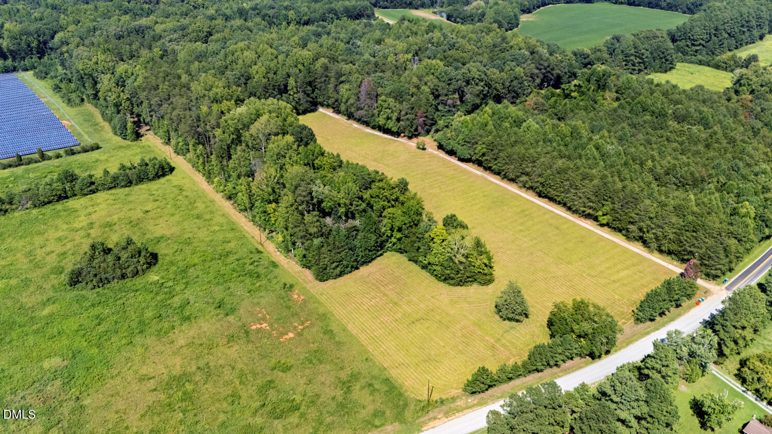 7391 Howerton Road Elon, NC 27244 - Photo 4 of 53 Expansive open fields bordered by mature trees and a paved road