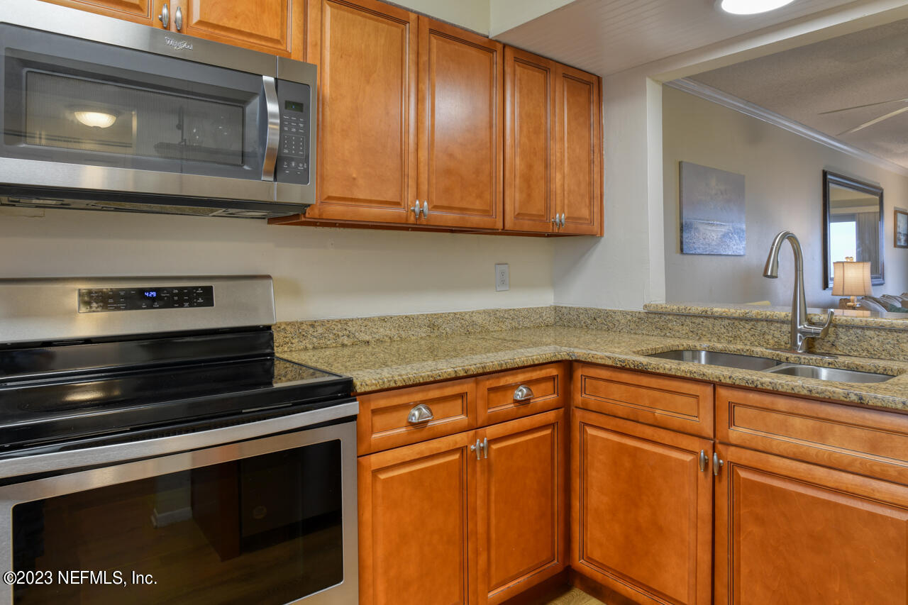 4 Ocean Trace Road, Unit 405 St. Augustine, FL 32080 - Photo 8 of 27 a kitchen with granite countertop cabinets stainless steel appliances and a sink
