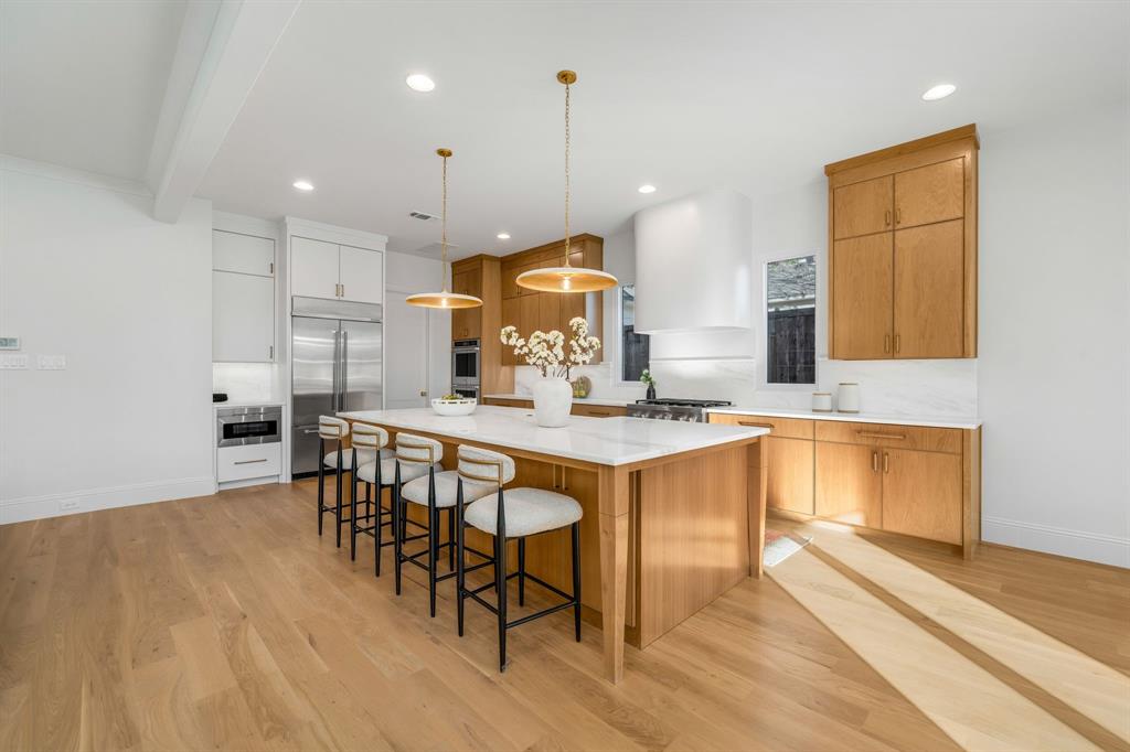 3884 Durango Drive Dallas, TX 75220 - Photo 5 of 16 a kitchen with granite countertop a stove a sink a dining table and chairs with wooden floor