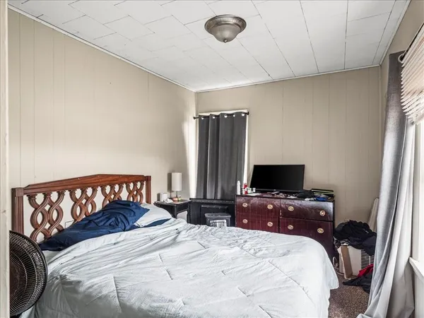 a bedroom with a bed and a flat tv screen on a dresser