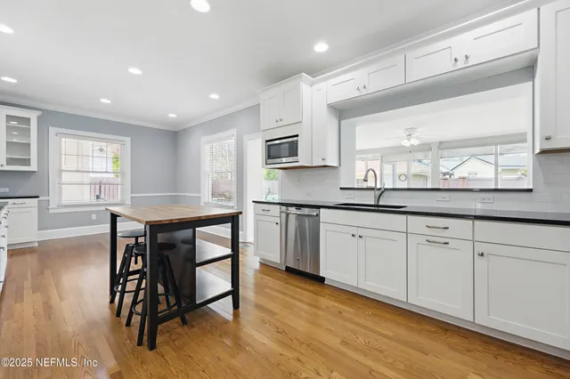 a kitchen with stainless steel appliances white cabinets a stove a sink and a microwave