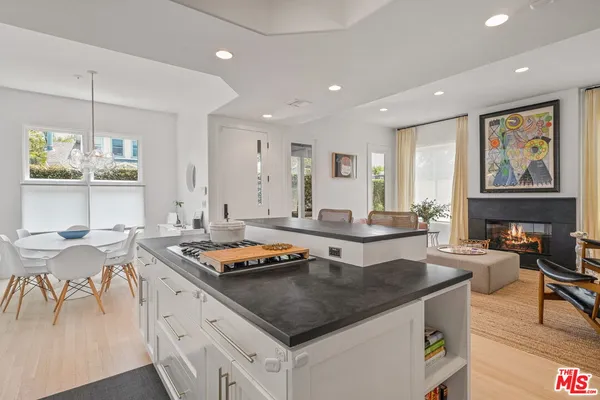 a kitchen with stainless steel appliances granite countertop a stove a sink a dining table and chairs with wooden floor