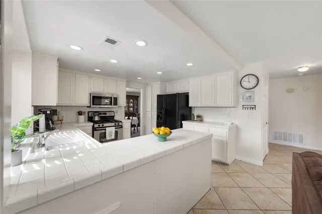 a kitchen with stainless steel appliances a refrigerator sink and white cabinets