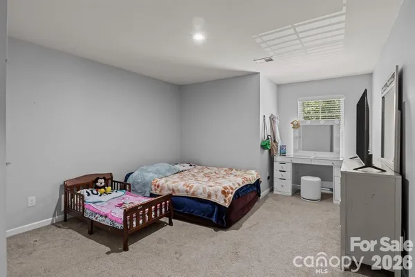 a bedroom with a bed and a flat tv screen on dresser