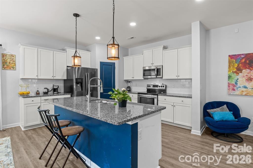 822 Lakehill Road Charlotte, NC 28214 - Photo 8 of 31 a kitchen with stainless steel appliances granite countertop a stove a refrigerator a sink a dining table and chairs with wooden floor