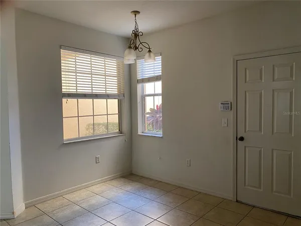 an empty room with chandelier fan and windows