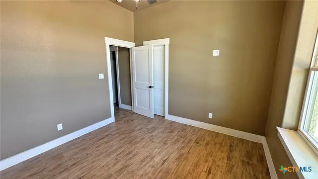 a view of an empty room with wooden floor and closet