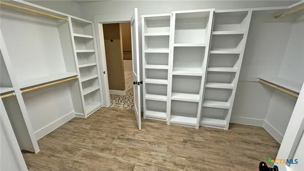 a view of an empty room with wooden floor and closet