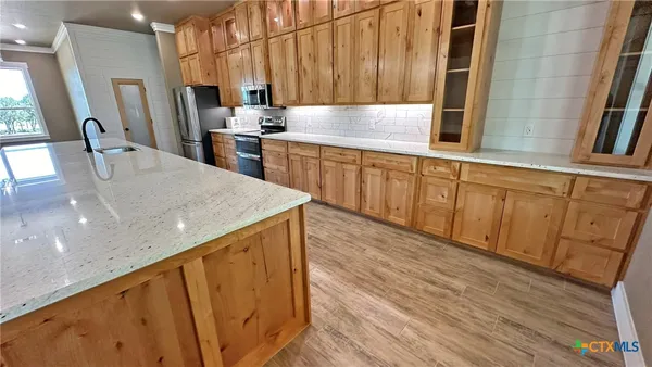 a kitchen with stainless steel appliances a refrigerator sink and wooden floor